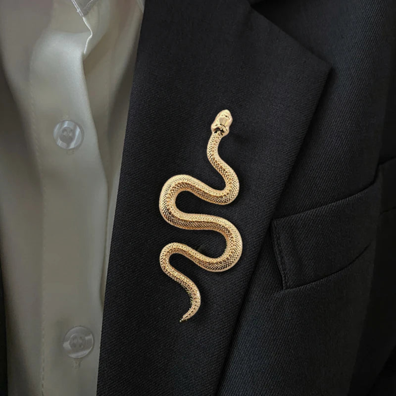 Gold snake brooch styled on a white blazer lapel.
