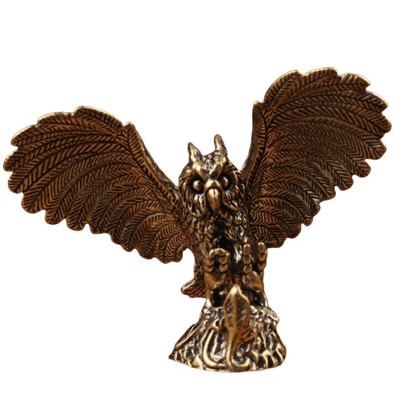 A bronze-finished metal owl figurine with wings spread wide, standing on a textured base against a plain white background.