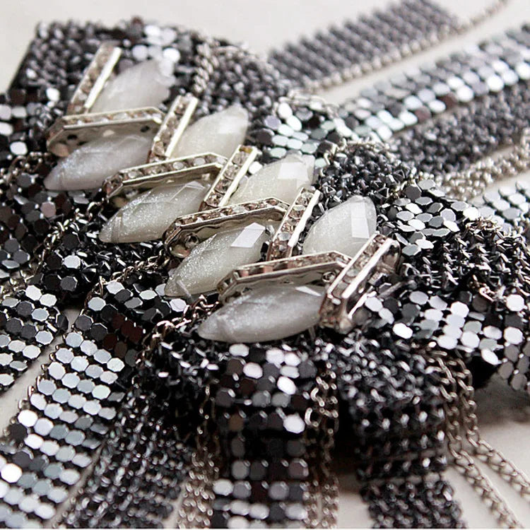 Close-up of crystal tassel shoulder brooch with metallic detailing.
