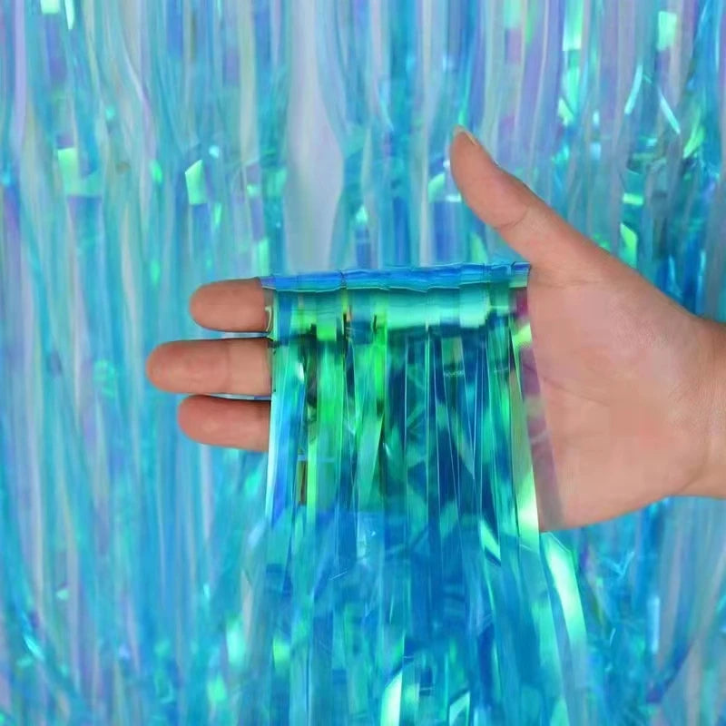 Hand holding a blue tinsel strip against a colorful tinsel curtain background