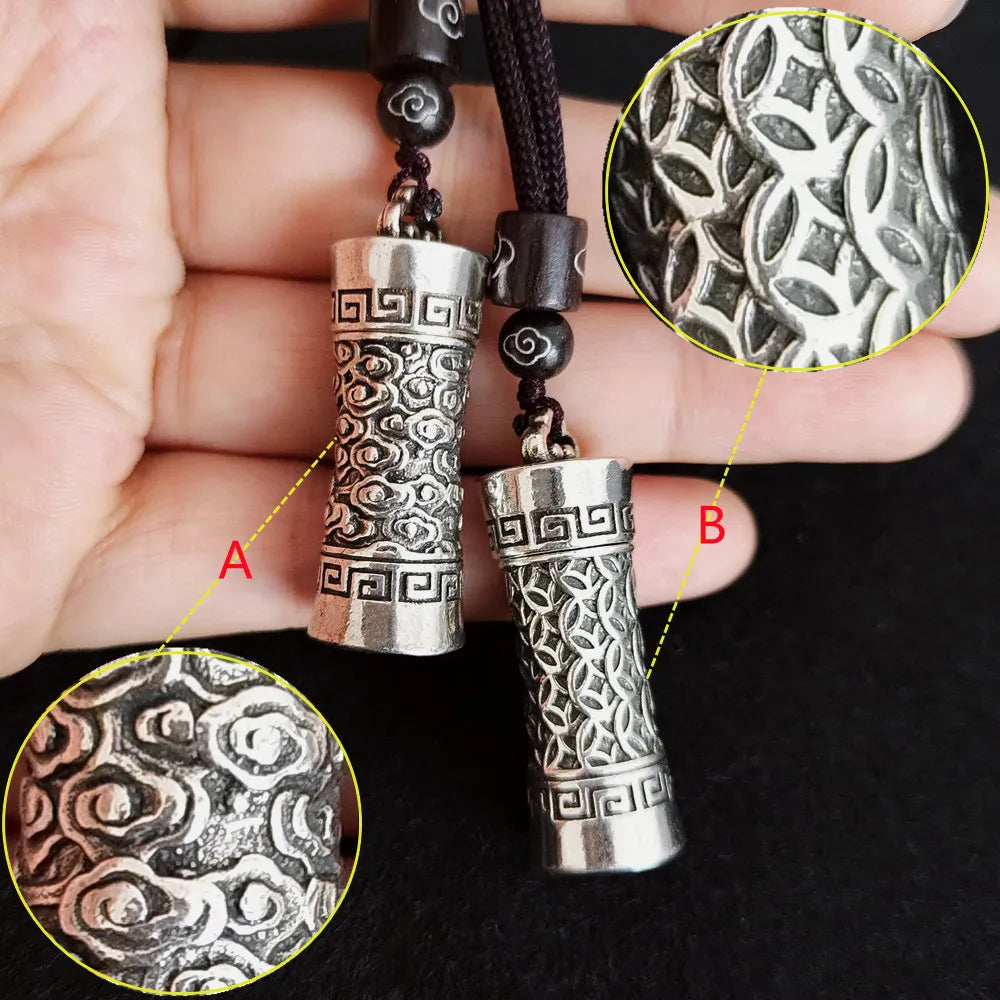 Close-up of silver cylindrical pendants with intricate patterns on a dark background