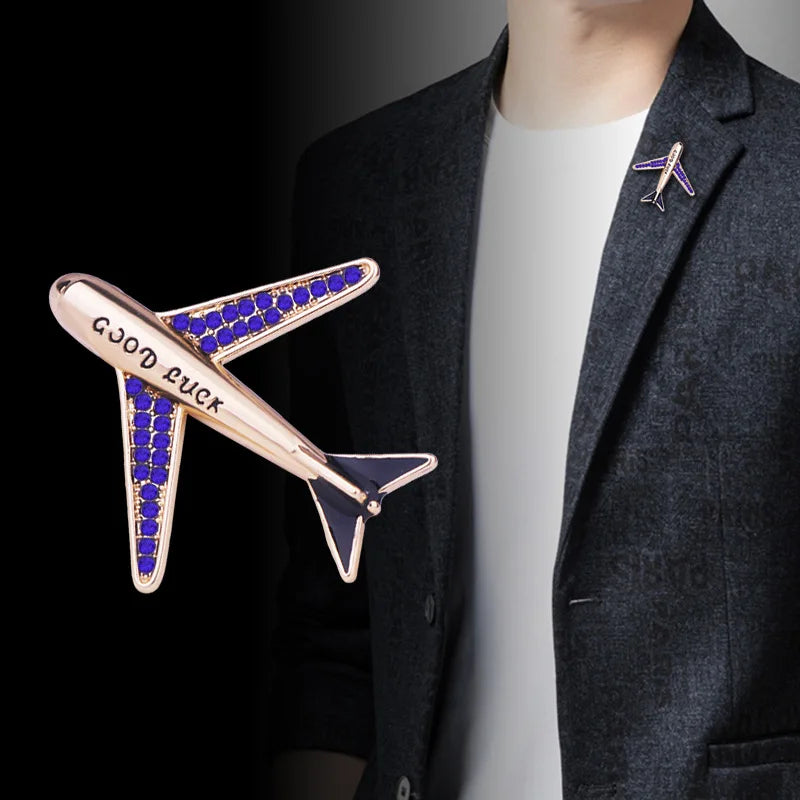 Airplane brooch pin with Good Luck engraving styled on a dark blazer lapel.