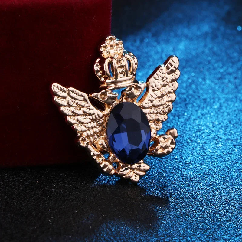 Gold angel brooch with blue gemstone luxury fashion jewelry on blue and red fabric background