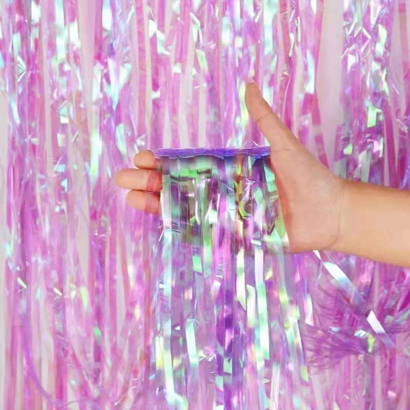 Hand holding a small container of purple tinsel against a background of pink and purple tinsel strands.