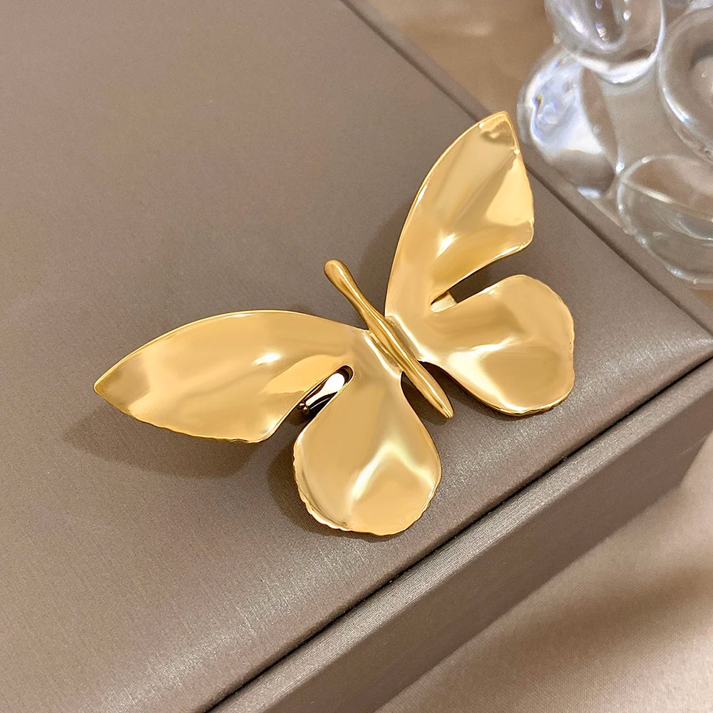 Gold butterfly-shaped brooch on a beige surface
