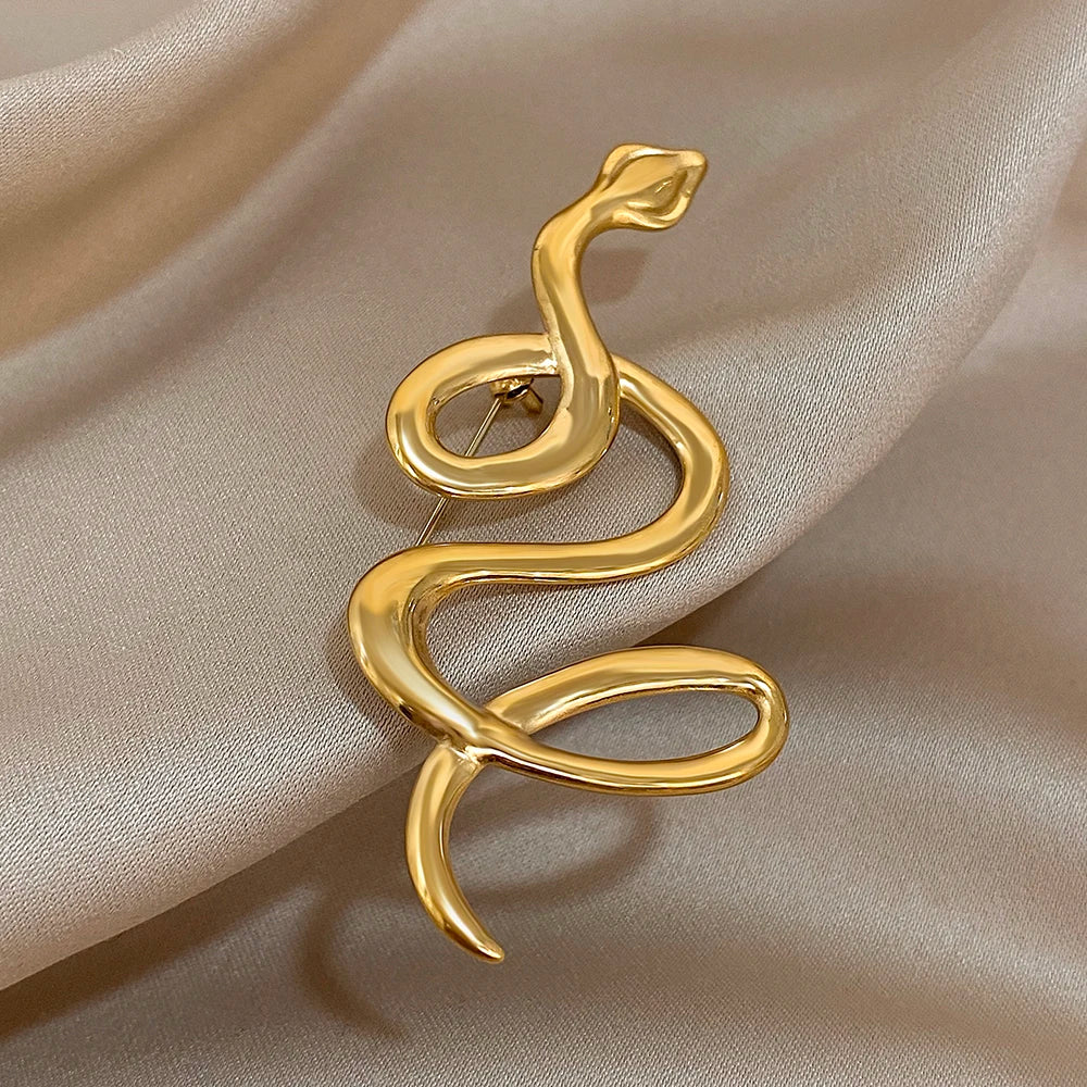 Gold snake-shaped brooch on a beige fabric background