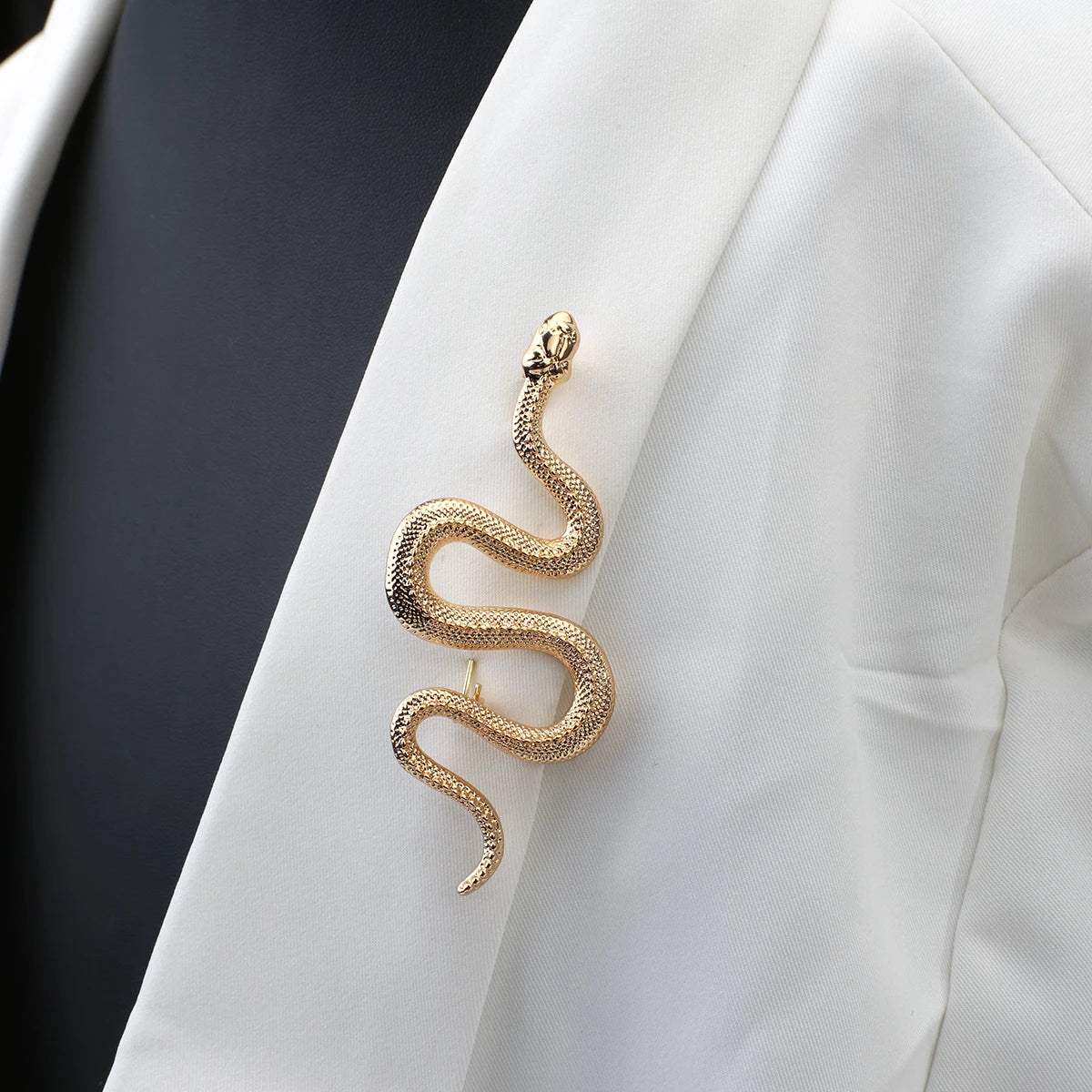 Elegant gold serpent brooch pin on white background.