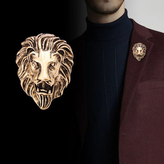 Man wearing a dark turtleneck and maroon blazer with lion head pins on a plain background