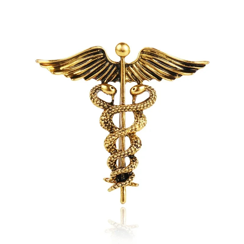Gold caduceus medical brooch on a white background