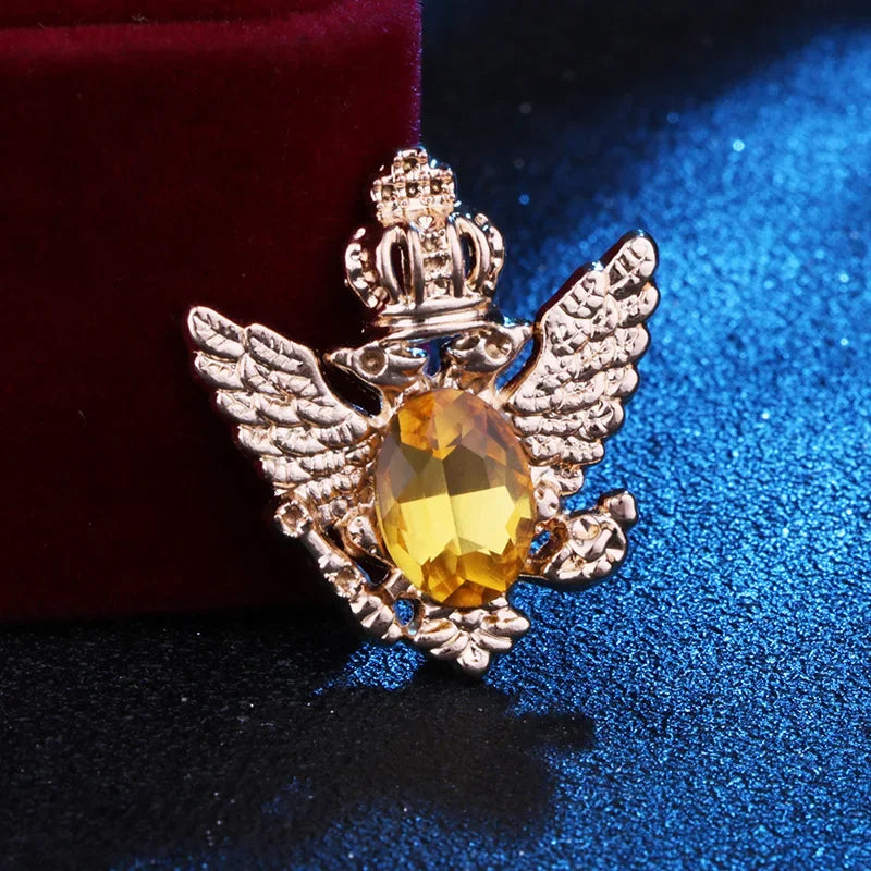 Gold angel brooch with yellow gemstone luxury fashion jewelry on blue and red fabric background