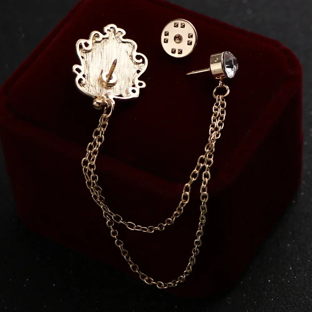 Gold brooch with chain and gemstone on a dark background