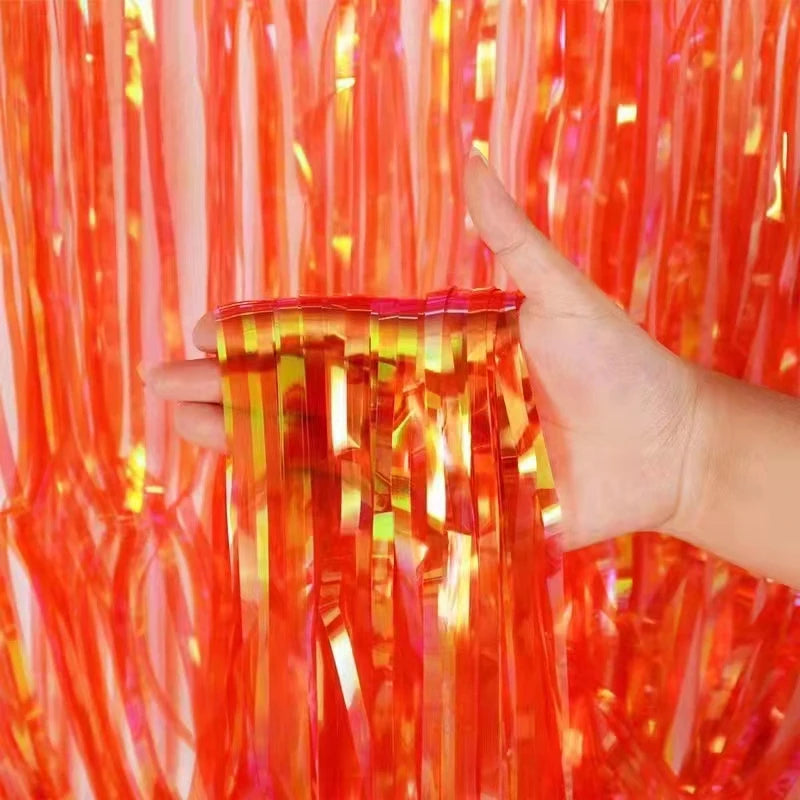 Hand holding a red plastic container with a colorful tinsel background