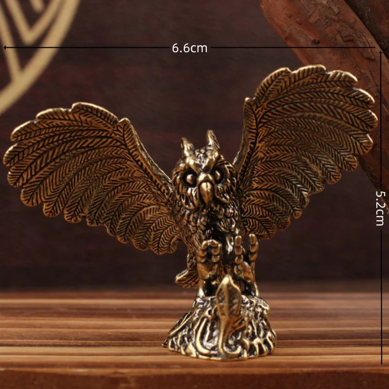 A bronze-toned metal owl figurine with wings spread wide, standing on an ornate base. White measurement lines and text show dimensions of 6.