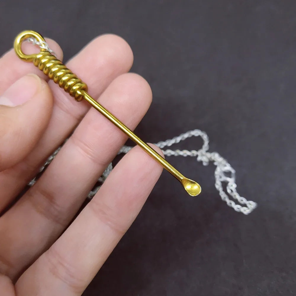 Mini metal spoon tool pendant held in hand featuring a polished antique gold finish