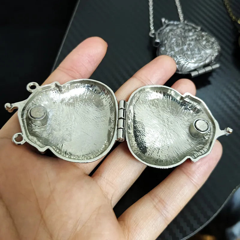 Silver locket held in a hand with a blurred background