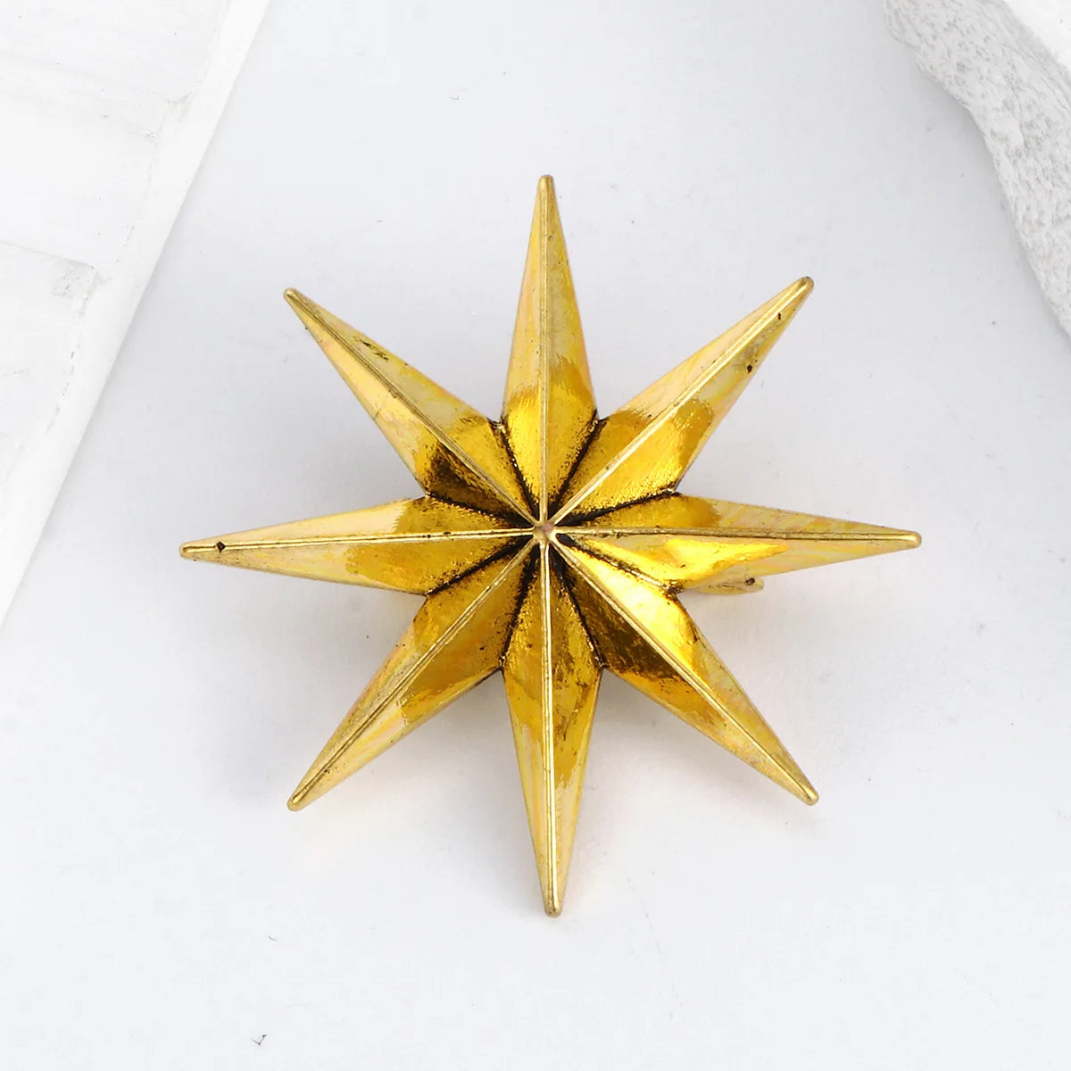 Metallic gold star lapel pin on white background