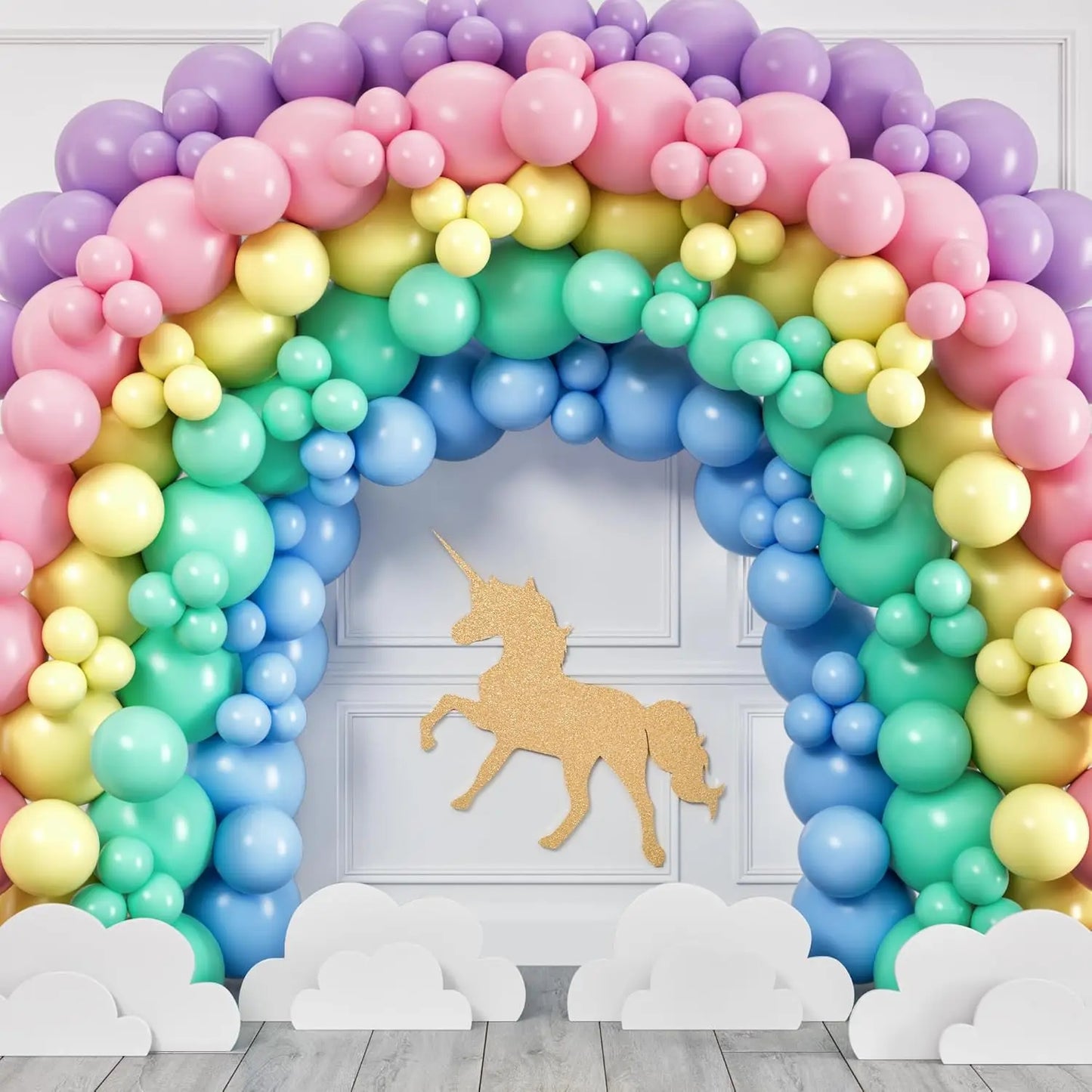 Colorful balloon arch with a gold unicorn cutout against a white wall.