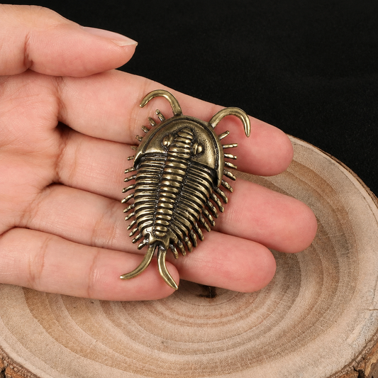 Vintage Brass Trilobite Figurine Held in Hand on Wooden Surface