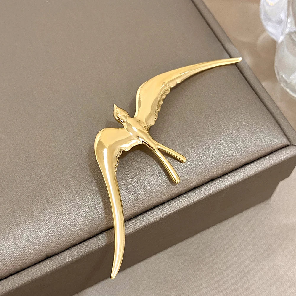 Gold bird-shaped decorative item on a beige surface