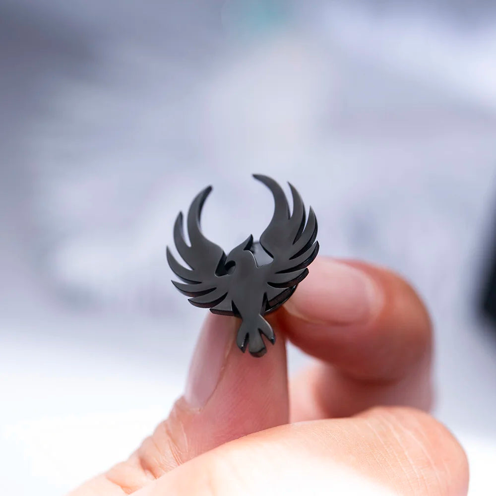 Black bird shaped earring held between fingers close up fashion jewelry shot