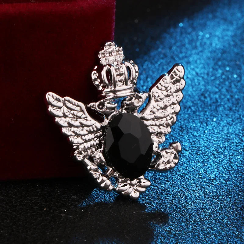 silver angel brooch with black gemstone luxury fashion jewelry on blue and red fabric background