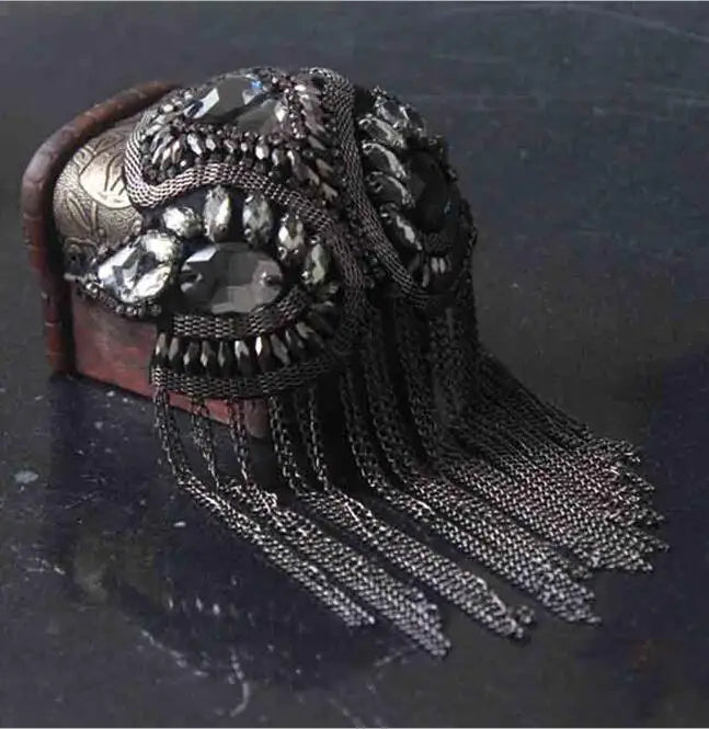 Intricate tassel shoulder jewelry with rhinestone detailing on dark background
