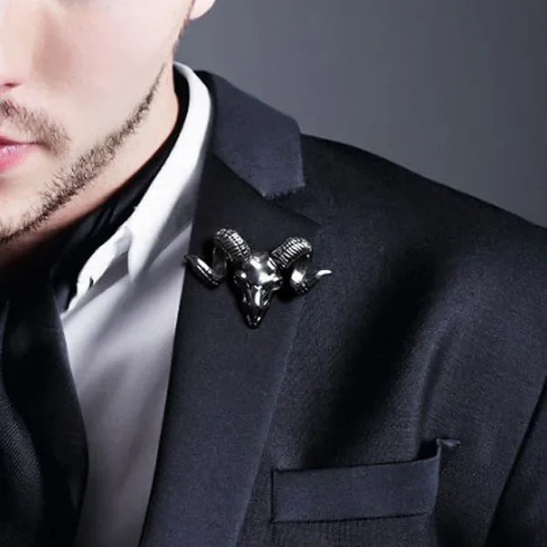 Man wearing a black suit styled with a vintage ram skull brooch pin.