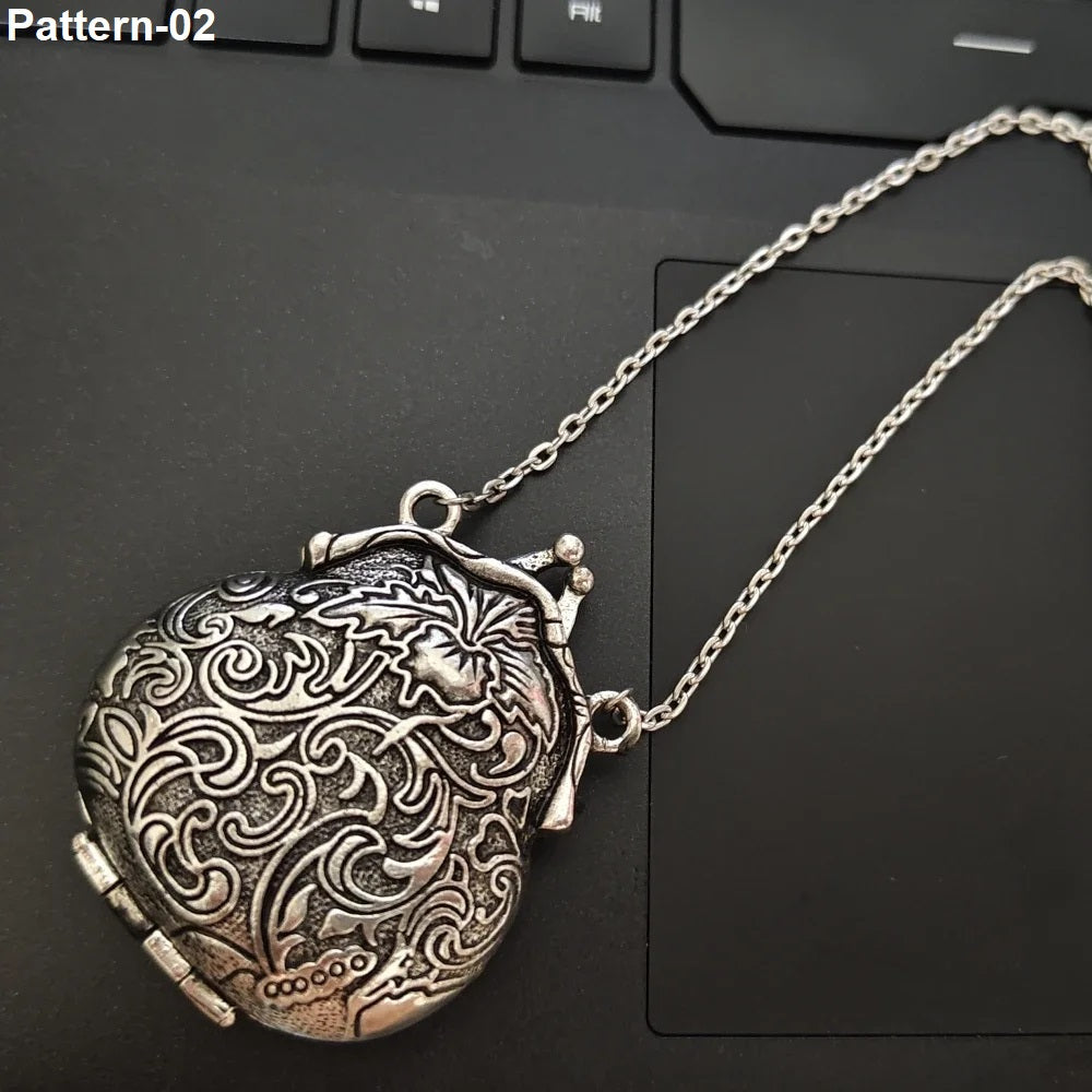 An antique silver heart-shaped locket pendant necklace with intricate floral engravings, resting on a black laptop keyboard. The text 'Pattern-02' is visible in the top-left corner.