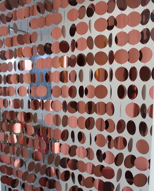 Decorative metallic sequin curtain panel with reflective circular discs and shimmering rose gold finish for party and event decoration.