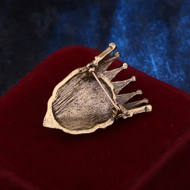 Vintage crown brooch displayed on red velvet cushion background