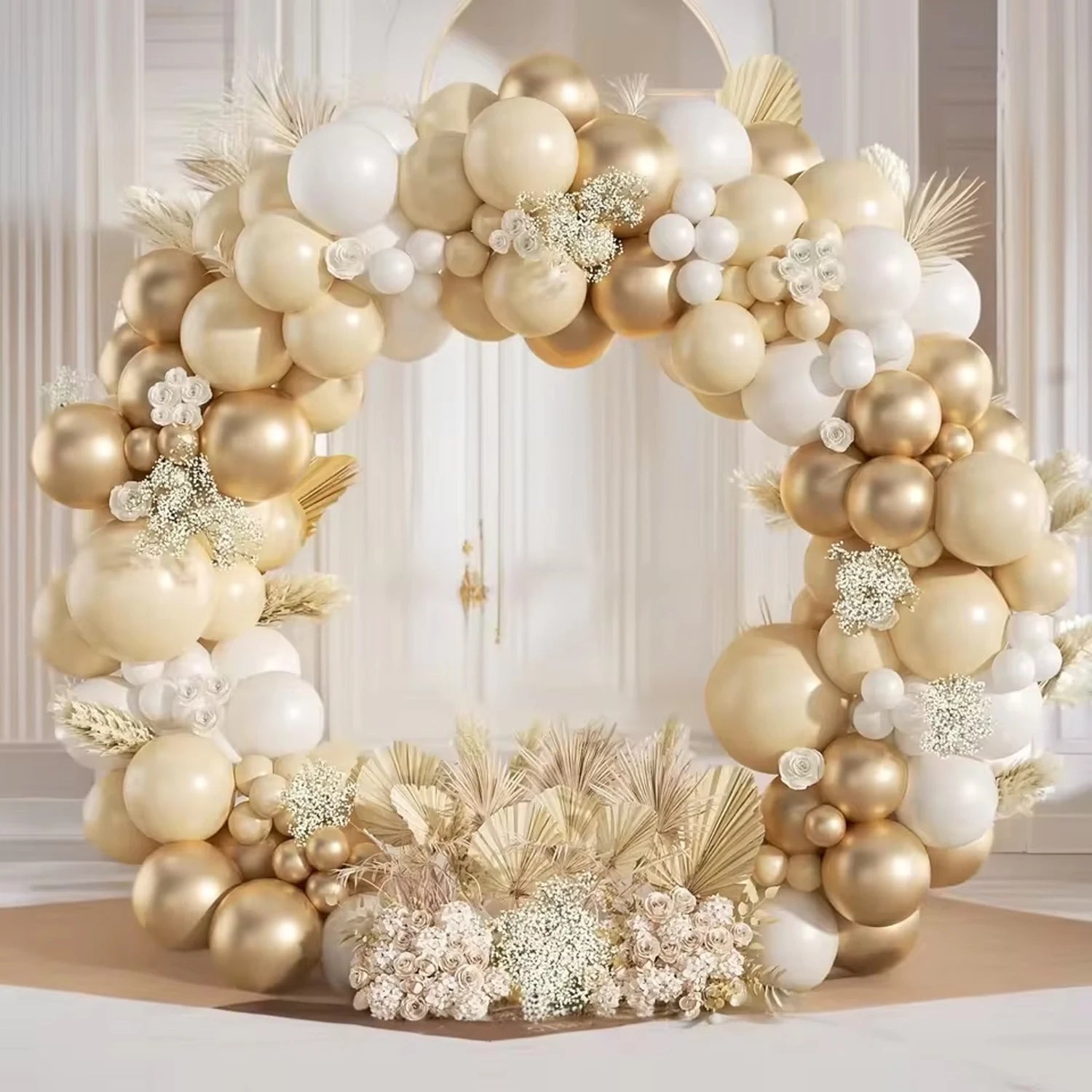 Decorative balloon arch with gold, white, and beige balloons and floral arrangements in a room.