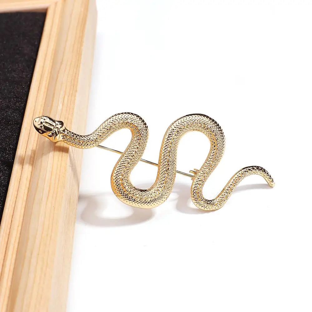 Gold snake-shaped brooch on a white background