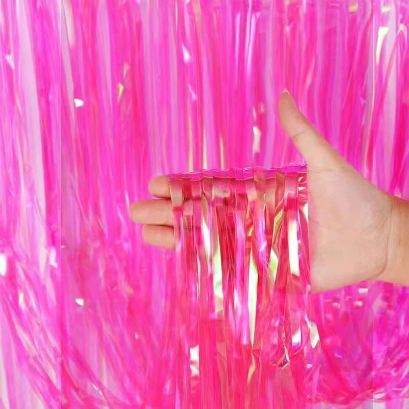 Hand holding a clear plastic strip against a vibrant pink tinsel background