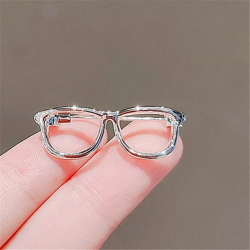 Minimalist transparent glasses brooch held between fingers
