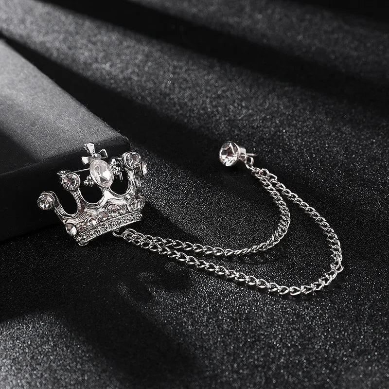 Crown-shaped brooch with chain on a black background