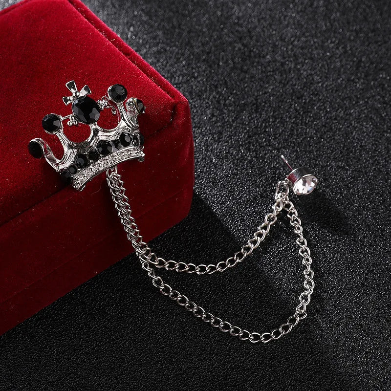 Crown-shaped brooch with chain on a dark surface