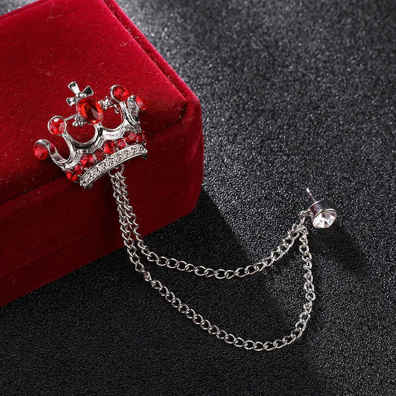 Decorative brooch with red gemstones and a chain on a dark surface