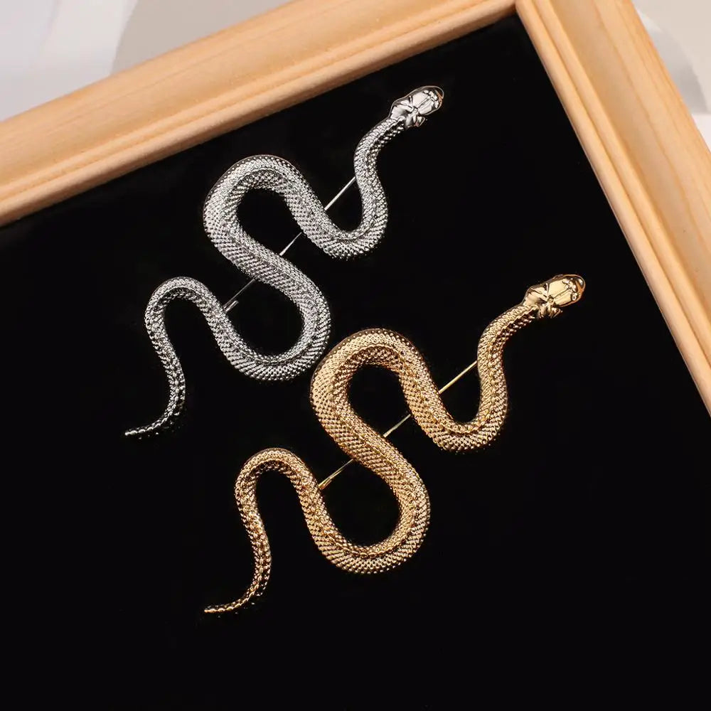 Gold and silver snake brooch pins displayed on black background.