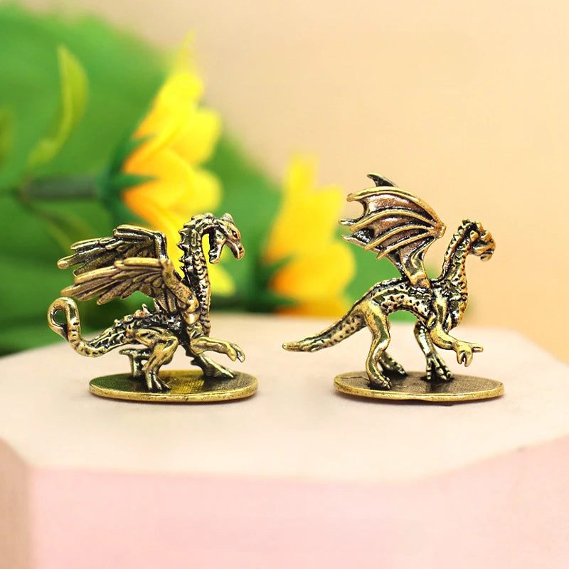 Two gold dragon figurines on a pink surface with a blurred floral background