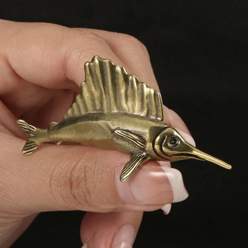 Solid brass sailfish figurine on a dark background