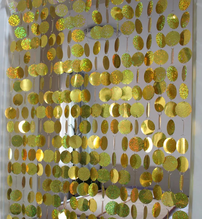 Gold circular disc decorative sequin hanging on a white background