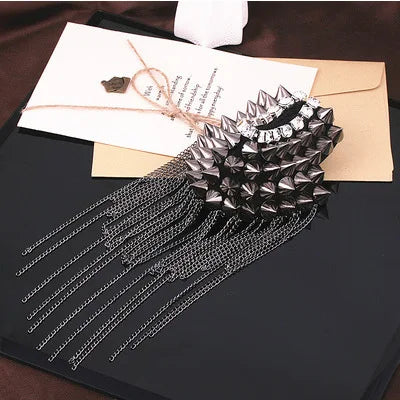 Black fashion accessory with spikes and chain tassels on dark surface