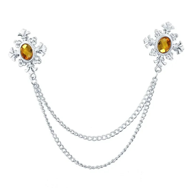 Silver Yellow Crystal cross collar brooch with decorative chain design on white background.
