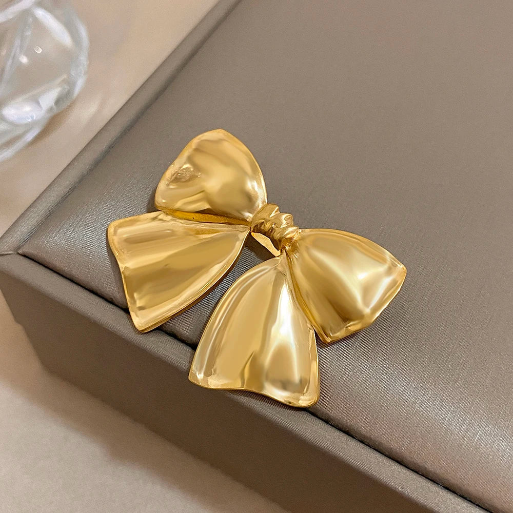 Gold bow-shaped brooch on a brown jewelry box