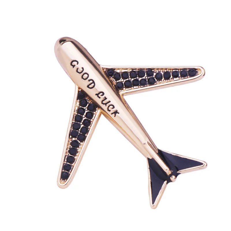 Rose gold airplane brooch with blue gemstone accents on white background.