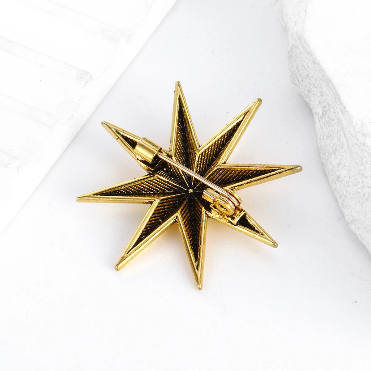 Gold star shaped brooch displayed on white fabric background