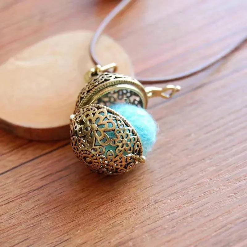 Hand holding vintage brass hollow ball locket pendant with floral pattern