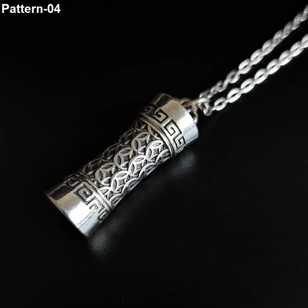 Silver cylindrical pendant with intricate patterns on a dark background