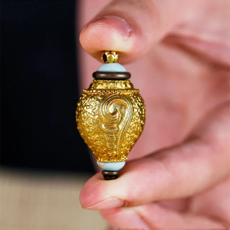 Antique brass conch shell pendant held in hand showcasing detailed craftsmanship and classic design
