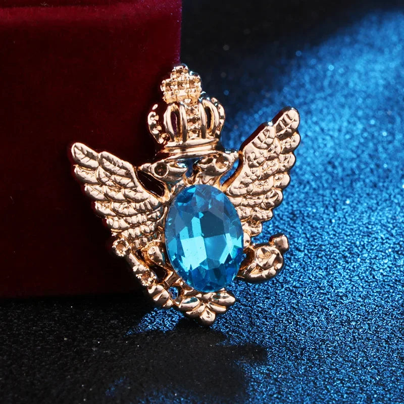 Gold angel brooch with sky gemstone luxury fashion jewelry on blue and red fabric background